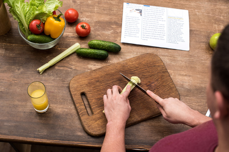 cropped shot of young man cutting celery on wooden chopping boardの写真素材
