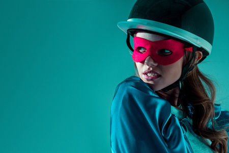 portrait of thoughtful woman in helmet, superhero mask and cape looking awayの写真素材