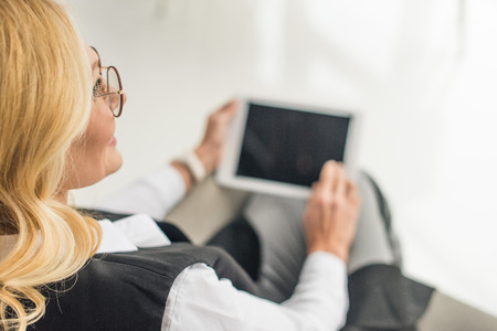 cropped shot of businesswoman in eyeglasses using digital tablet with blank screen