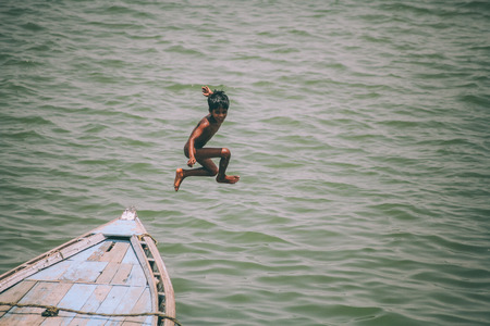adorable little boy jumping from boat in Varanasi, Indiaの写真素材