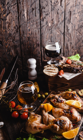 tasty grilled meat with vegetables and beer on wooden backgroundの写真素材