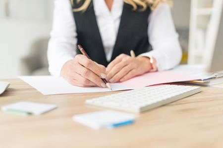 cropped shot of businesswoman doing paperwork at workplaceの写真素材
