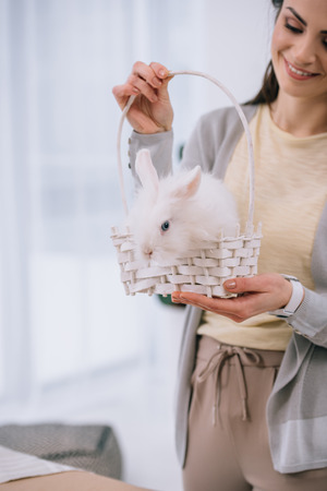attractive young woman with white rabbit in basketの写真素材