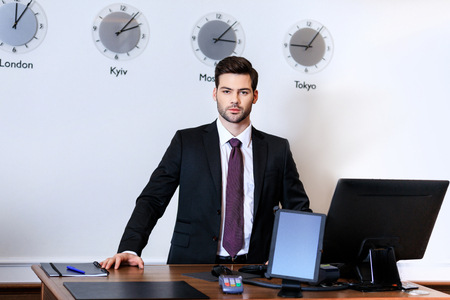 handsome receptionist standing at reception desk in hotelの写真素材