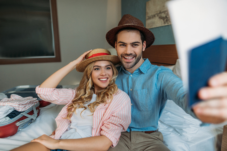 smiling couple holding passports with tickets in hotel roomの写真素材