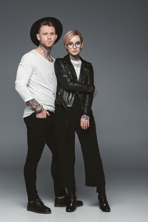 fashionable tattooed couple posing together, isolated on greyの写真素材