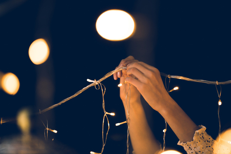 cropped shot of woman hanging beautiful garland on black backgroundの写真素材