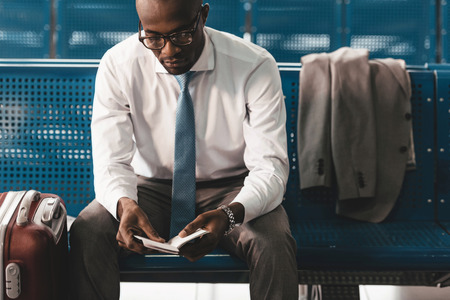 businessman reading book while waiting for flight at airport lobbyの写真素材