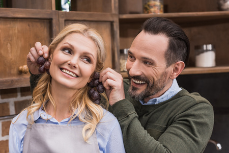 husband making earrings to wife with grapesの写真素材