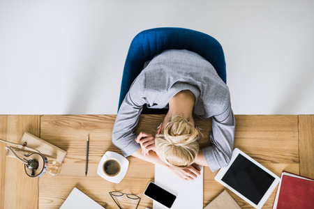 overhead view of tired businesswoman sleeping on workplace in officeの写真素材