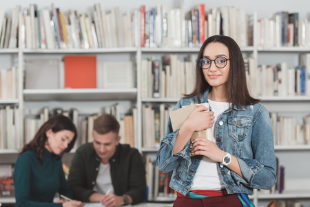 african american girl standing with books in libraryの写真素材