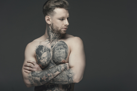 shirtless tattooed man with crossed arms, isolated on greyの写真素材