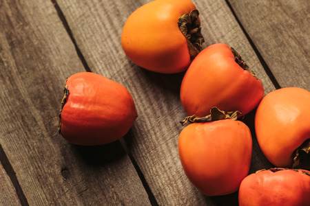 scattered ripe persimmons on wooden gray surface