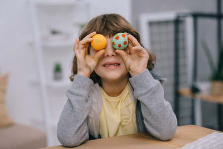 little kid covering eyes with easter eggs