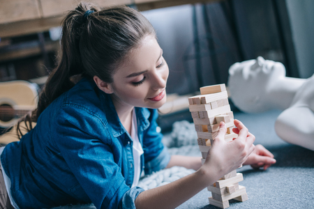 selective focus of woman playing blocks wood game with layman doll near by at home, perfect relationship dream conceptの写真素材