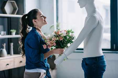 young woman pretending to receive flowers from layman doll, perfect relationship dream conceptの写真素材