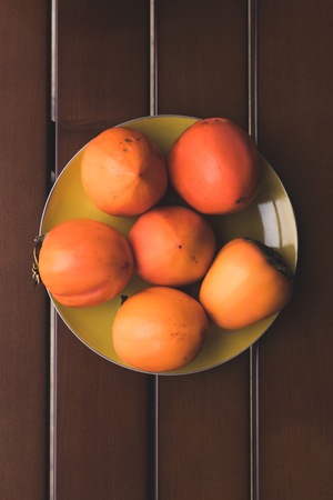 top view of yellow plate with orange persimmonsの写真素材