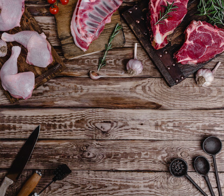 top view of various raw meat and kitchen utensils on wooden tableの写真素材