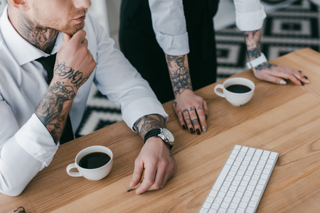 cropped shot of young business people with tattoos working together at tableの写真素材