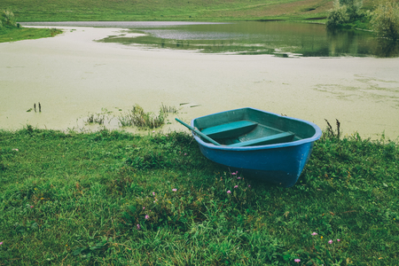blue boat on green grass near beautiful river in Altai, Russiaの写真素材
