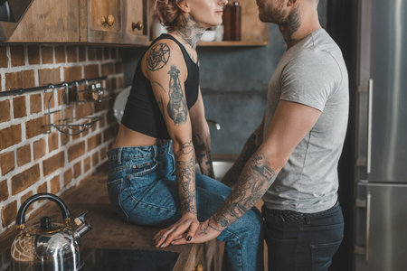 cropped view of young tattooed couple together in kitchenの写真素材