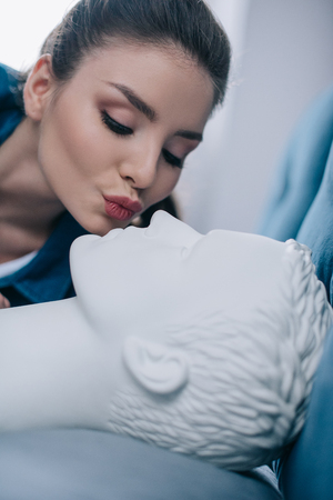 close up view of woman kissing mannequin in bed, one way love conceptの写真素材