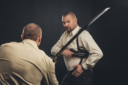 mafia members fighting with gun and katana sword on blackの写真素材