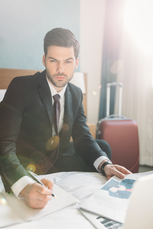businessman sitting on bed with newspaper and notebookの写真素材