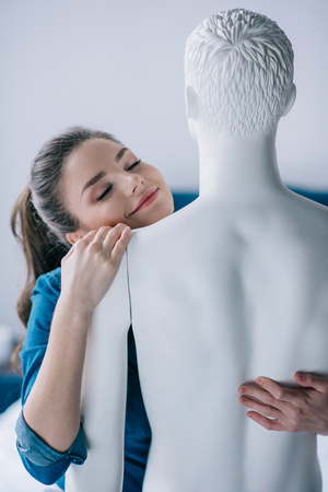 smiling young woman hugging layman doll, one way love conceptの写真素材