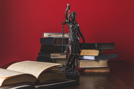 opened juridical books with lady justice statue on wooden table, law conceptの写真素材