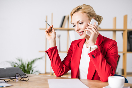 portrait of businesswoman talking on smartphone at workplace in officeの写真素材