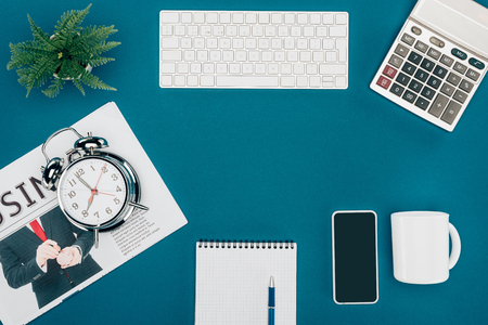 top view of computer keyboard, smartphone, calculator and clock on blueの写真素材