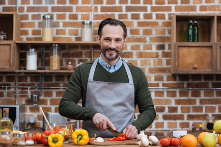 handsome man cutting vegetables in kitchenの写真素材