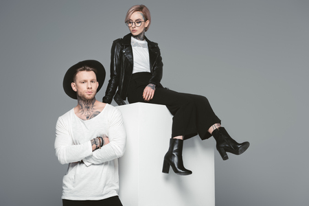 beautiful stylish young couple with tattoos posing together isolated on greyの写真素材