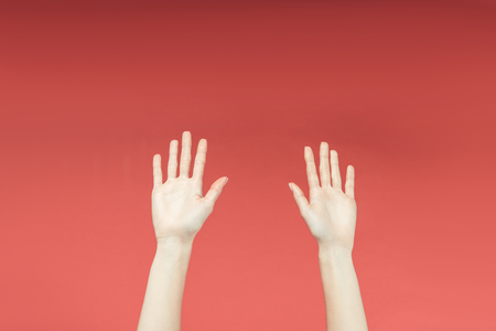 cropped view of female hands raised up, isolated on redの写真素材