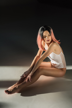 beautiful sensual woman with pink hair posing in white lace bodysuitの写真素材