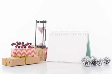 close up view of blank calendar, sand clock, pine cones and wrapped gifts isolated on white