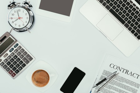 top view of laptop, smartphone, contract with pens, alarm clock and calculator on whiteの写真素材