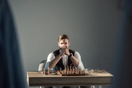 selective focus of stylish businessman with cigar looking at camera while playing chessの写真素材
