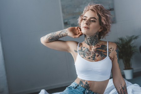 beautiful stylish inked girl stretching in bed at morningの写真素材