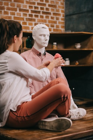 woman pretending to feed mannequin with cupcake at home, perfect relationship dream conceptの写真素材