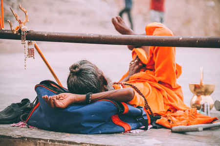 monk in bright orange clothing resting in Varanasi, Indiaの写真素材