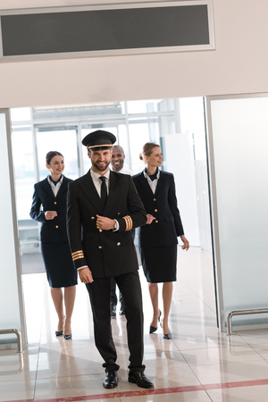 handsome young pilot walking by airport with his teamの写真素材