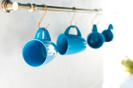 selective focus of empty blue cups hanging in kitchenの写真素材