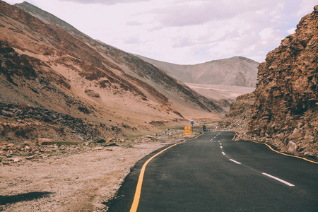 asphalt road with traffic signs in Indian Himalayas, Ladakh regionの写真素材