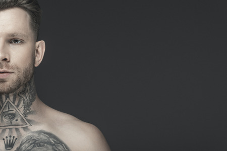 cropped view of young shirtless tattooed man, isolated on greyの写真素材