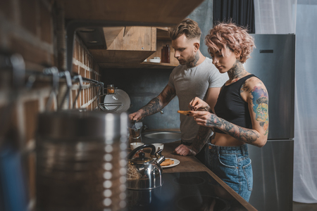 tattooed couple making breakfast at kitchenの写真素材