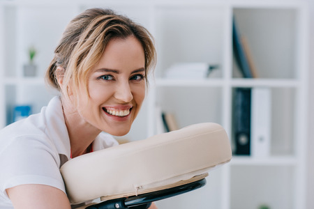 close-up portrait of attractive woman sitting on massage chair at officeの写真素材