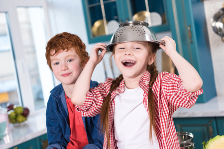 adorable happy little kids having fun and smiling at camera in kitchenの写真素材