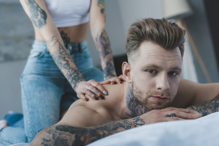 cropped view of tattooed girlfriend doing massage for her boyfriendの写真素材